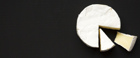 Cheese camembert or brie on dark black background. Milk production. Overhead view. Flat lay, from above. Space for text.の写真素材