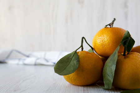 Fresh ripe unpeeled tangerines over white wooden background, side view. Copy space.の写真素材