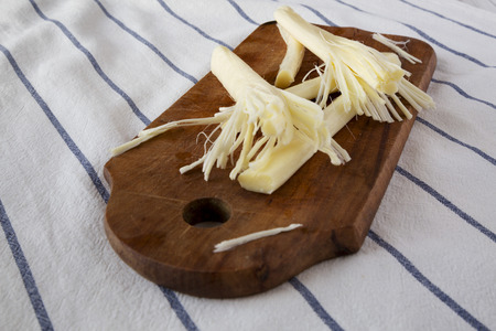 String cheese on rustic wooden board on cloth, side view. Healthy snack. Close-up.の写真素材