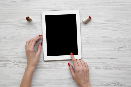 Feminine workspace with tablet in female hands, lipstick, overhead view. Flat lay, from above, top...