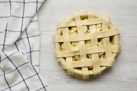 Raw apple pie on white wooden background, overhead view. From above, flat lay, top view.の写真素材