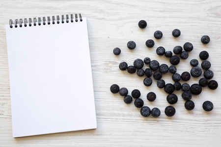 Top view, blueberries and blank notepad on a white wooden background. Space for text.の写真素材