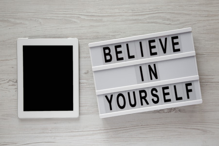 Lightbox with text 'Believe in yourself', tablet on a white wooden background, top view. From above, flat lay, overhead.の写真素材