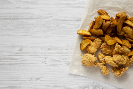Fastfood: fried potato wedges, chicken bites on a white wooden background, top view. Flat lay,...