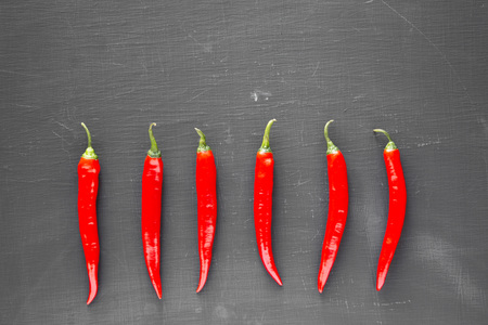 Hot red chili peppers on black background, top view. From above, overhead, flat lay. Copy space.