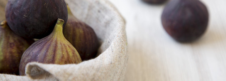 Fresh figs in a bowl on a white wooden background, side view. Closeup.