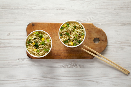 Tasty instant ramen noodles with beef flavoring on rustic wooden board, top view. Flat lay, from...