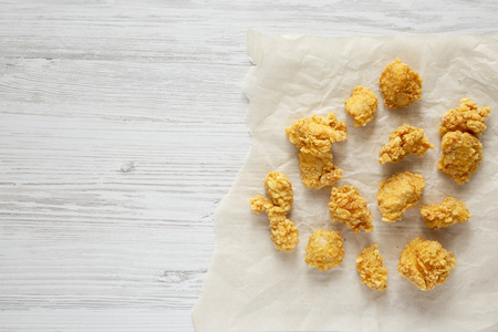 Chicken bites over white wooden surface, top view. Flat lay, overhead, from above. Copy space.