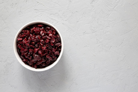 Dry organic cranberries in a bowl over concrete background, top view. Overhead, from above, flat...