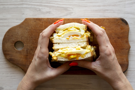 Female hands hold homemade egg sandwich, top view.の写真素材