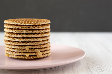Stack of sweet Dutch stroopwafels with honey-caramel filling on pink plate, side view. Copy space.の写真素材