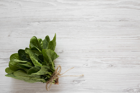 Fresh raw spinach on a white wooden background. Flat lay, overhead, from above. Copy space.の写真素材
