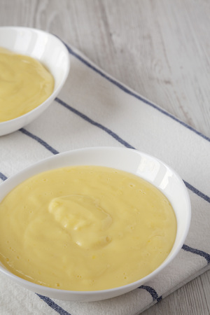 Homemade vanilla custard pudding in white bowls, low angle view. Space for text.の写真素材