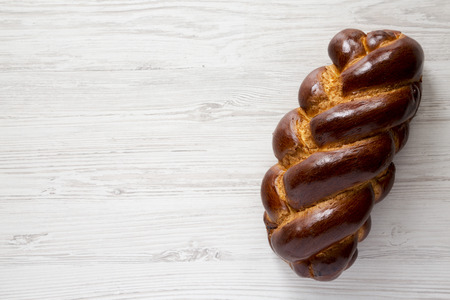 Homemade jewish challah bread on a white wooden surface, top view. Overhead, from above, flat lay. Copy space.の写真素材