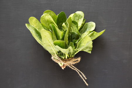 Fresh raw spinach on a black background, top view. Flat lay, overhead, from above.