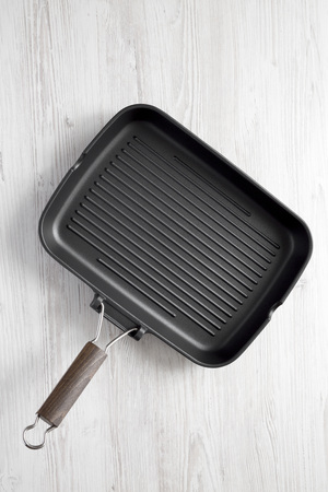 Empty grill pan on a white wooden surface, top view. Overhead, from above, flat lay. Close-up.の写真素材