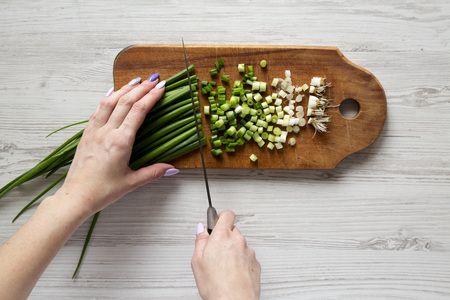 Woman chopping green onions, top view. Overhead, from above.