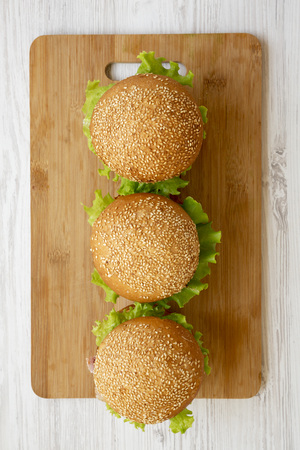 Homemade cheeseburgers on a bamboo board over white wooden surface, overhead view. Flat lay, from above. Close-up.の写真素材