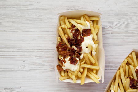 French fries with cheese sauce and bacon in paper boxes, top view. Flat lay, from above, overhead. Copy space.の写真素材