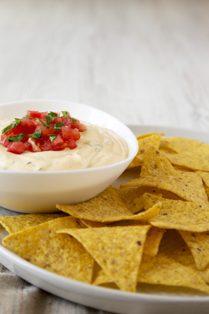Homemade cheesy dip in a bowl, yellow tortilla chips, side view. Copy space.の写真素材