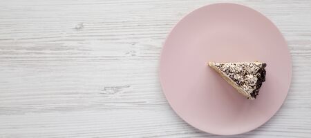 A piece of tiramisu cake on a pink plate on a white wooden table, top view. Space for text.の写真素材