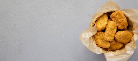 Chicken nuggets in a paper box, ketchup on a gray background. Overhead, from above, flat lay. Space for text.の写真素材