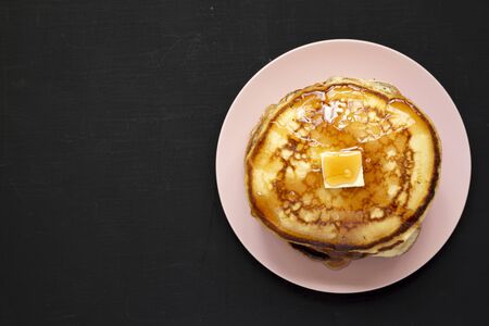 Homemade pancakes with butter and maple syrup on a pink plate, top view. Flat lay, top view, from above. Copy space.の写真素材