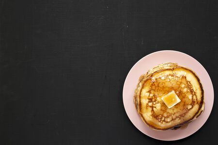 Homemade pancakes with butter and maple syrup on a pink plate, top view. Flat lay, overhead, from above. Space for text.の写真素材