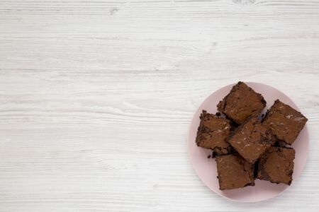 Homemade chocolate brownies on a pink plate on a white wooden background, top view. Flat lay, overhead, from above. Copy space.の写真素材