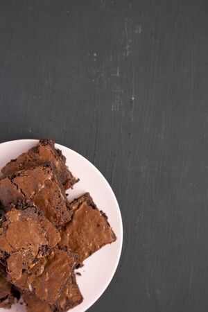 Homemade chocolate brownies on a pink plate on a black background, top view. From above, overhead, flat lay. Copy space.の写真素材