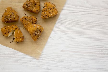 Fried camembert on a baking sheet on a white wooden surface. Flat lay, overhead, from above. Copy...