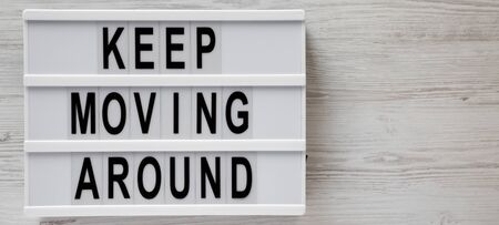 A lightbox with 'Keep moving around' words over white wooden background, top view. From above, flat lay, overhead. Copy space.の写真素材