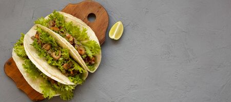 Shrimp tacos on a rustic wooden board on a gray background. Flat lay, from above, overhead. Mexican cuisine. Space for text.の写真素材