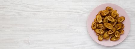 Homemade fried plantains on a pink plate over white wooden background, view from above. Flat lay, top view, overhead. Space for text.の写真素材