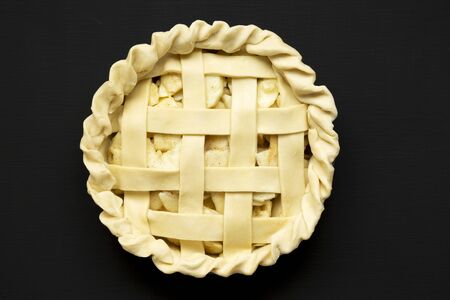 Raw apple pie on a black background, top view. Flat lay, overhead, from above. Close-up.の写真素材