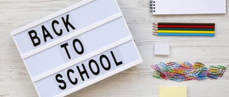 'Back to school' words on a modern board, accessories for study on a white wooden background, overhead view. Top view, flat lay, from above.の写真素材