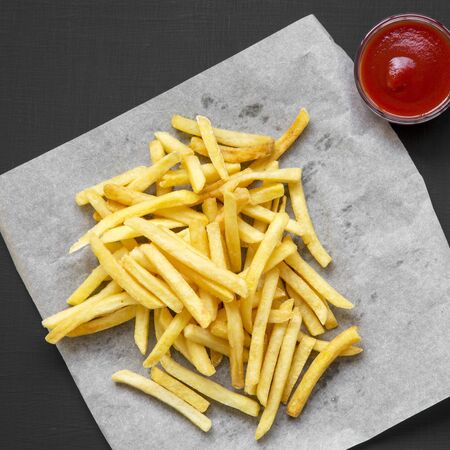Fresh fried tasty french fries with sauce on a black background, overhead view. From above, top view.の写真素材