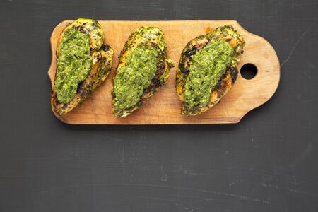 Grilled chimichurri chicken breast on a rustic wooden board on a black background, top view. Flat lay, overhead, from above. Copy space.の写真素材