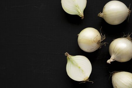 Raw white onions on a black surface, top view. Flat lay, overhead, from above. Copy space.の写真素材