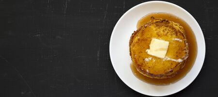 Homemade corn meal Johnny cakes on a white plate on a black surface, top view. Flat lay, overhead, from above. Copy space.の写真素材