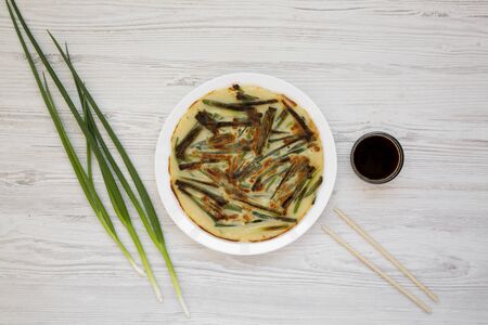 Homemade korean Pajeon scallion pancake on a white plate on a white wooden table, top view. Asian food. Flat lay, overhead, from above.の写真素材