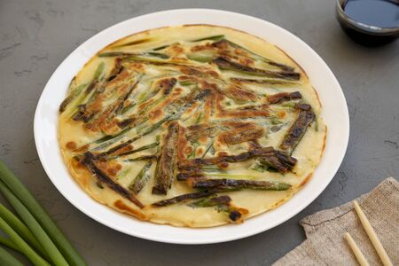 Homemade korean Pajeon scallion pancake on a white plate on a gray background, side view. Asian food. Close-up.の写真素材