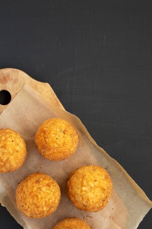 Top view, homemade fried Arancini on a rustic wooden board on a black surface. Italian rice balls. Flat lay, from above, overhead. Space for text.の写真素材
