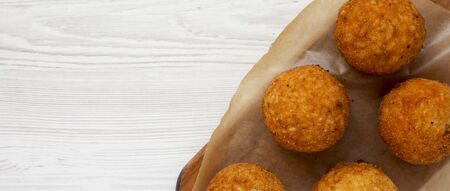 Homemade fried Arancini on a rustic wooden board on a white wooden background, top view. Italian rice balls.の写真素材