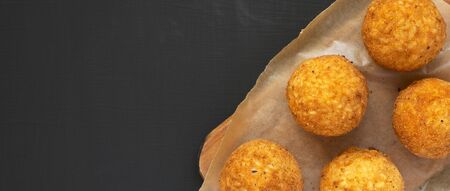 Homemade fried Arancini on a rustic wooden board on a black background, top view. Italian rice balls.の写真素材