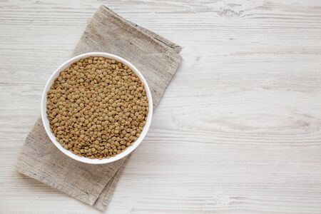 Organic green lentils in a white bowl on a white wooden background, top view.の写真素材