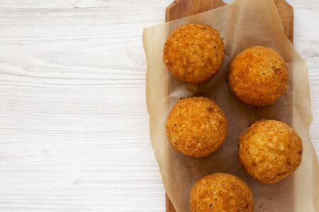 Homemade fried Arancini on a rustic wooden board on a white wooden surface, top view. Italian rice balls. Flat lay, from above, overhead. Space for text.の写真素材