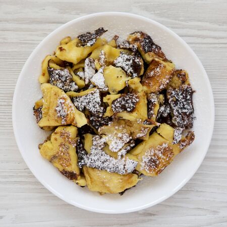Homemade german Kaiserschmarrn pancake on a white plate on a white wooden surface, top view. Flat lay, overhead, from above. Close-up.の写真素材