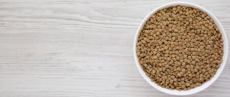 Organic green lentils in a white bowl on a white wooden table, top view. Flat lay, overhead, from above. Space for text.の写真素材