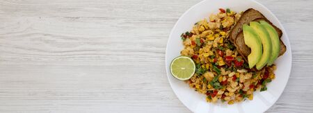 Homemade southwestern egg scramble with toast on a white plate on a white wooden surface. Flat lay, overhead, from above. Space for text.の写真素材
